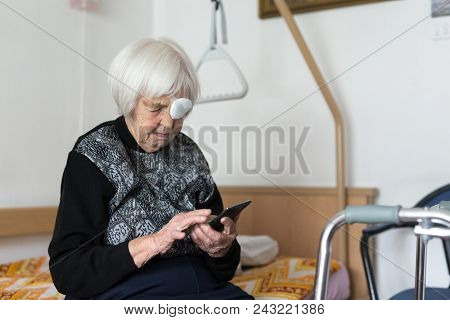 Lonley Elderly 95 Years Old Woman Sitting At The Bad Using Modern Mobile Phone Application To Monito
