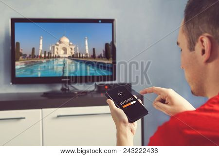 The Guy Is Browsing With The Phone Pictures On A Big Tv Via Wifi. Nformation Transfer Between Device