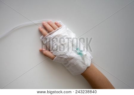 Kid Hand With An Elastic Bandage  With The Tube Of Normal Saline Infusion.