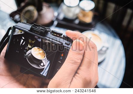 Photography Blogging Workshop Concept. Hand Holding Camera Taking Photo Of Coffee In Coffee Shop.