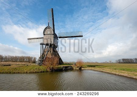 Backside Of Dutch Wooden Hollow Post Mill Against A Cloudy Sky. The Mill, A Dutch National Monument,