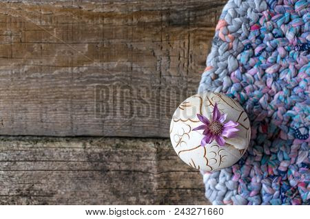 One Lilac Flower Xeranthemum On Round Clay Vase On Knitted Patchwork And Gray Wooden Background Text