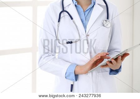 Woman Doctor Using Tablet Computer While Standing Straight In Hospital Closeup. Healthcare, Insuranc