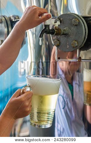 Pouring Sparkling Wine In Glass Jug At Winery.