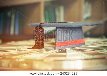 Graduation Cap On Dartboard Target In Old Library Stack Of Text Literature On Table With Bookshelves