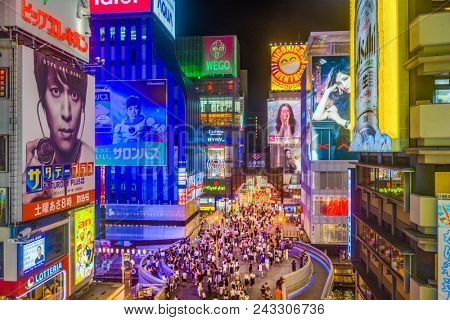 OSAKA, JAPAN - AUGUST 16, 2015: Pedestrians walk below billboards in the Dotonbori district. The district is a popular tourist attraction.