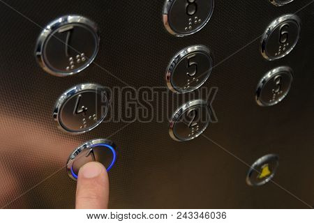 Close-up. The Index Finger Of The Male Hand In The Elevator Presses The First Floor Button, Which Gl