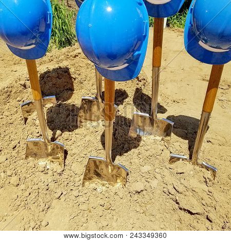 Industrial Blue Hard Hats On Shovels In Dirt For Ground Breaking Ceremony