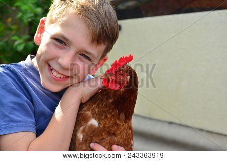 A Boy Is Holding A Brown Chicken And Smiling