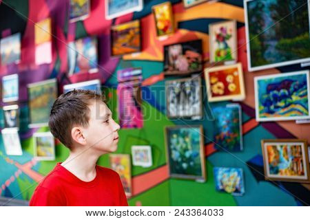 The Guy On The Exhibition Of Paintings And Photographs Carefully Looks At The Painting And Enjoys Ar