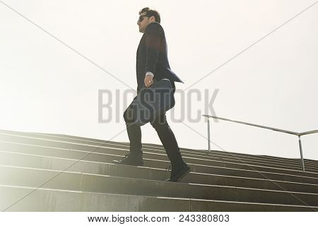 Young Confidental Businessman Wearing Suit And Running Fast Upstairs. Horizontal Outdoors Shot.