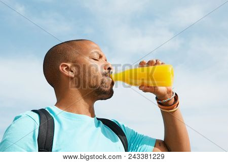 Healthy Organic Drinks. Portrait Of Dark Skinned Guy Drinking Tasty Fresh Orange Juice. African Man 