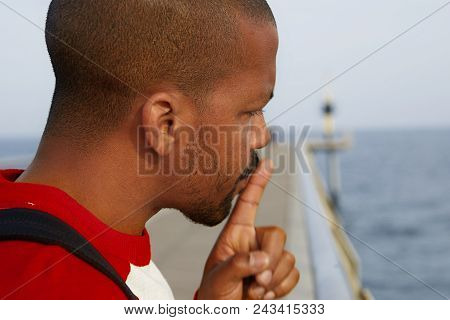 Close Up Portrait Of Handsome Cheerful Silent American African Man Making Hush Gesture At The Beach