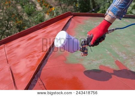 The Hand Holds The Sprayer And Paints The Roof