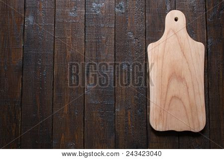 Light Wooden Cutting Board, On A Brown Wooden Table. View From Above. Vertical Line. Free Space. Sid