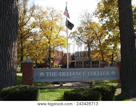 Defiance College Sign And Flag Pole With The United States Of America Flag Surrounded By Fall Foliag