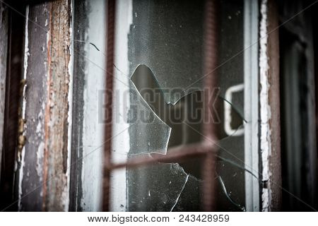 Smashed Glass Window With Old Wooden Frame On Grunge Wall Damaged House
