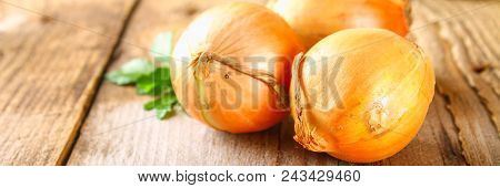 Yellow Onion With Parsley On A Wooden Table