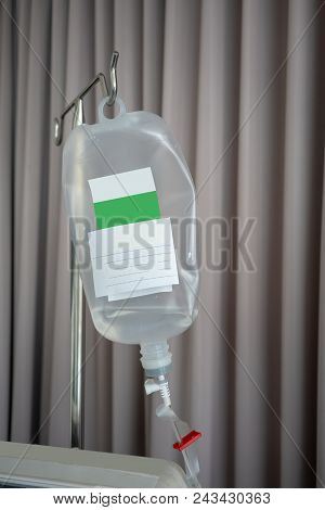 Normal Saline Solution For Patient In The Hospital Against Fabric Curtain Background