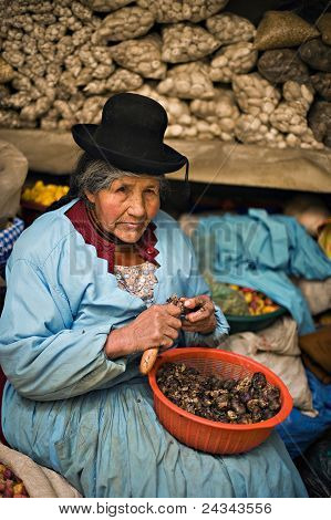 Peruwiański kobieta skórki ziemniaków na rynku, Puno, Peru