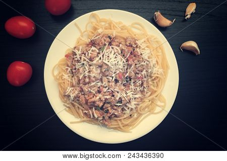 Appetizing Spaghetti In A Plate With Bolognese Sauce On A Dark Background, Garlic And Tomatoes