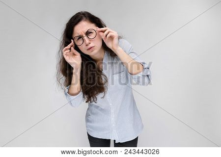 A Young Girl In A Light Blouse And Dark Trousers. The Girl Looks At Herself In The Mirror.