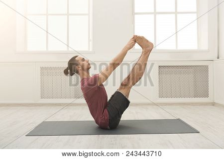 Young Man Practicing Yoga With Gymnastic Mat, Making Corner Stretching Exercise, Copy Space