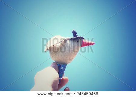 A Bird In A Black Hat, A Handmade Toy, On A Blue Sky Background