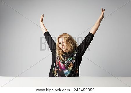 Beautiful Happy Blonde Women Raised Her Hands Up And Smiling Against On Gray Background. Studio Shot