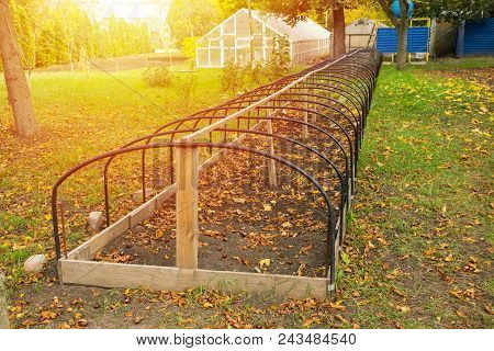 Metal Frame Of Unheated  Greenhouse In An Autumn Park. Preparation Of Greenhouses For Autumn, Winter