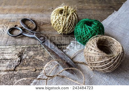 Three Brown And Green Thread Ball With Antique Vintage Scissors On Textured Old Wooden Boards. Rusti