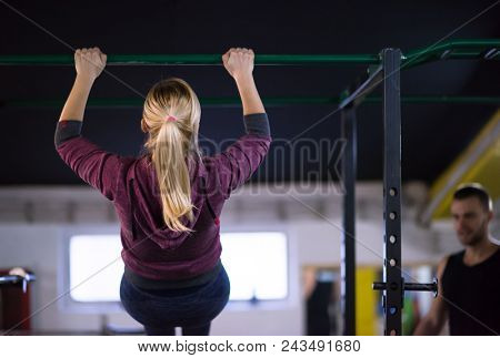 young muscular woman doing pull ups on the horizontal bar as part of Cross fitness Training
