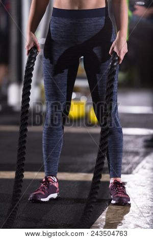 young fit athlete woman working out in functional training gym doing  battle ropes exercise as part of cross fitness training