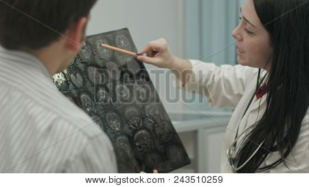 Female Doctor In Clinic Show X-rays To Male Patient