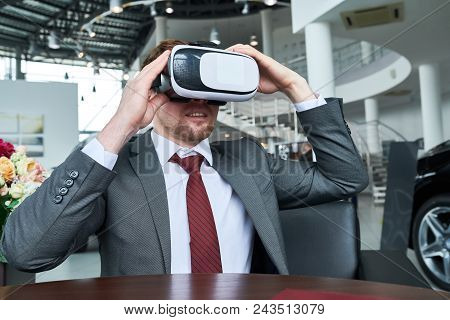 Bearded Customer Wearing Classical Suit Sitting At Wooden Table And Using Vr Headset While Undergoin