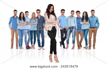 confident young casual team with businesswoman leader standing in front with crossed hands and legs, smiling on white background