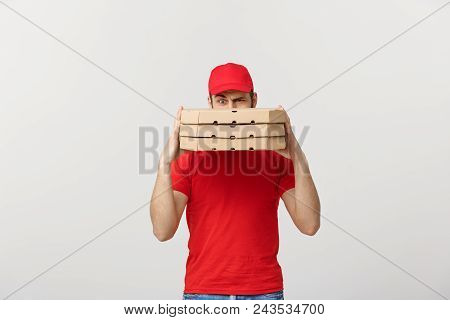 A Deliveryman Hidden Behind A Large Stack Of Pizza Boxes He Is Carrying. Isolated Over Grey Backgrou