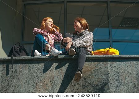 College Students Making Plans For The Future Chatting Happy. Young Girls With Reddish Hair Sit On A 