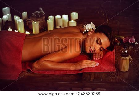 Massage of woman in spa salon. Girl on candles background in massage spa salon. Luxary interior in oriental therapy salon. Summer discounts on spa treatments. Anti-cellulite measures.