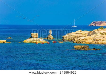 The oarsmen on the red canoe. Picturesque coastline. Island of Cyprus in the Mediterranean Sea. Concept of active and ecological tourism