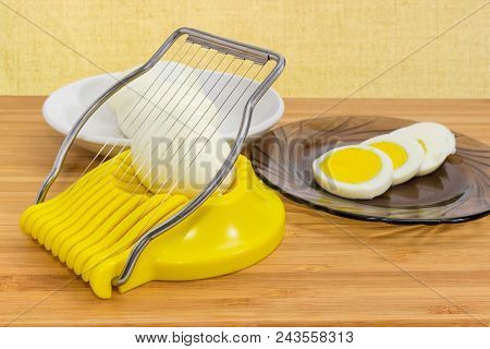 Egg Slicer With Egg In It, Sliced And  Whole Peeled Boiled Eggs On A Different Saucers On A Wooden B