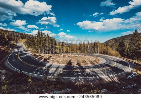 Highway with hairpin turn (switchback) at autumn sunny day in Rocky Mountain National Park. Colorado, USA. 