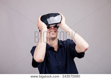 Excited Man Experiencing Virtual Reality For The Firts Time. He Is Wearing A Vr Headset. Gray Backgr