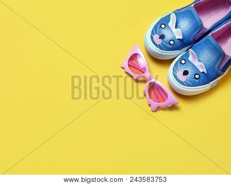 Kid's Shoes And Pink Sunglasses On Yeallow Background. Top View, Flat Lay. Place For Text. Fashion C