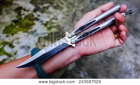 Butterfly Knife (balisong) In Male Hand On A Gray Background