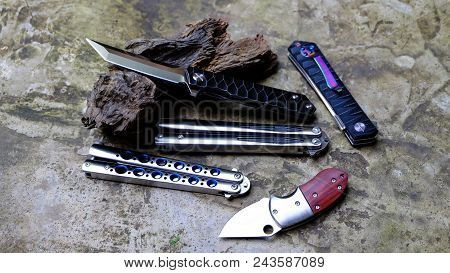 Butterfly Knife (balisong), Tanto Knife, Small Knife In A Folded State Against A Old Wooden Floors B