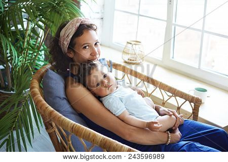 Picture Of Nine Month Old Cute Chubby Baby Boy Resting In Tender Embrace Of His Cheerful Beautiful M