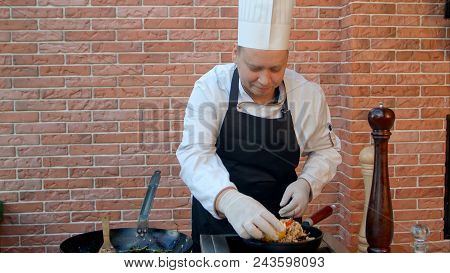 Handsome Male Chef Dressed In White Uniform Decorating Paella And