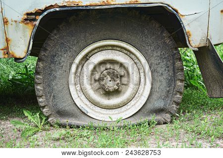 Flat Tire On An Old Rusty Suv Close-up. Abstract Background.