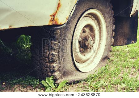 Flat Tire On An Old Rusty Suv Close-up. Abstract Background.